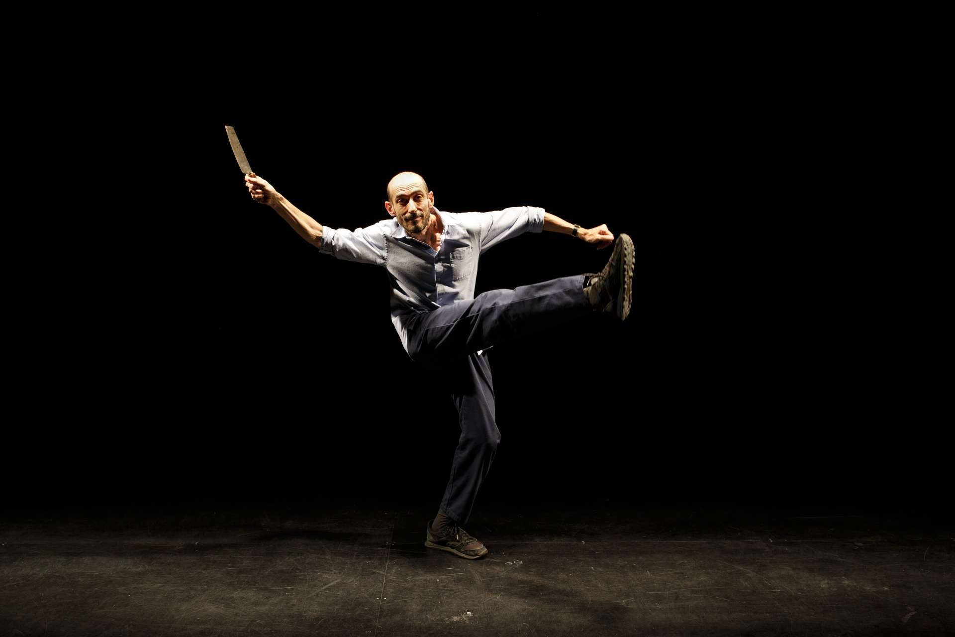 Eric Feldman sur scène danse la jambe gauche et le bras droit levés