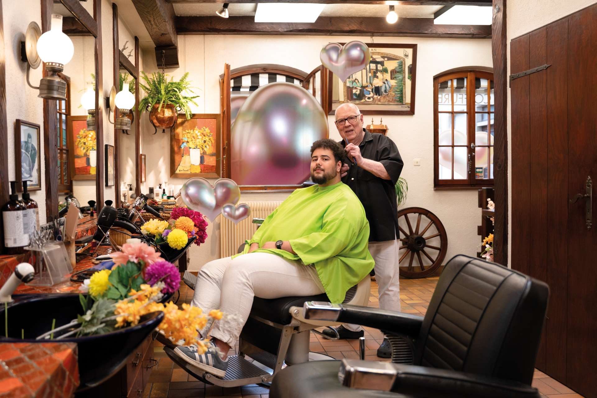 Jean coiffeur agé dans un salon à la décoration de bois passée coiffe un jeune homme 