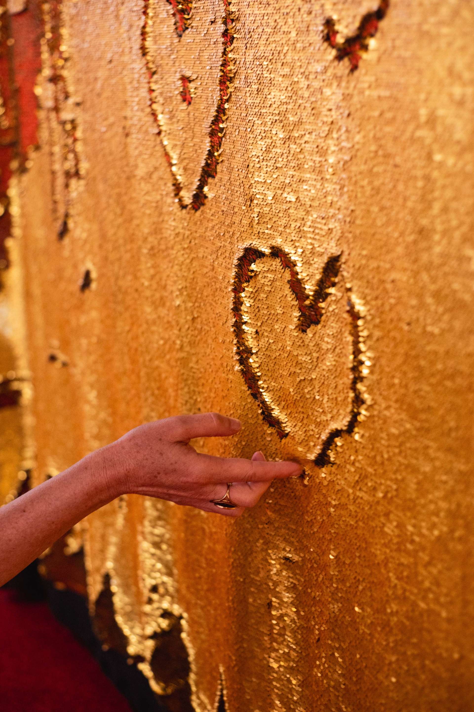 coeur desiné par une main sur un tissu de sequin doré