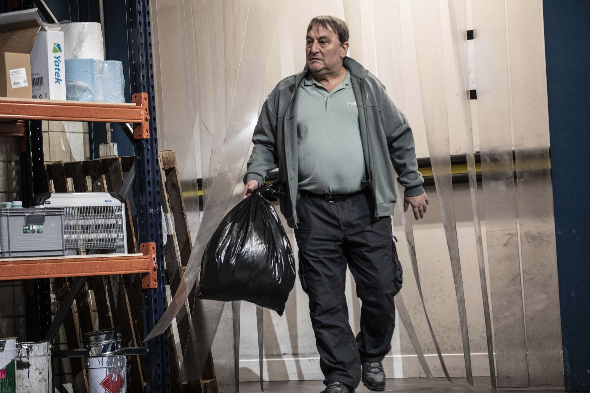 Prendre soin Alexander Zeldin © Jean-Louis Fernandez un acteur dans un décor industriel et entouré de produits nettoyants avance un sac de dechet noir à la main
