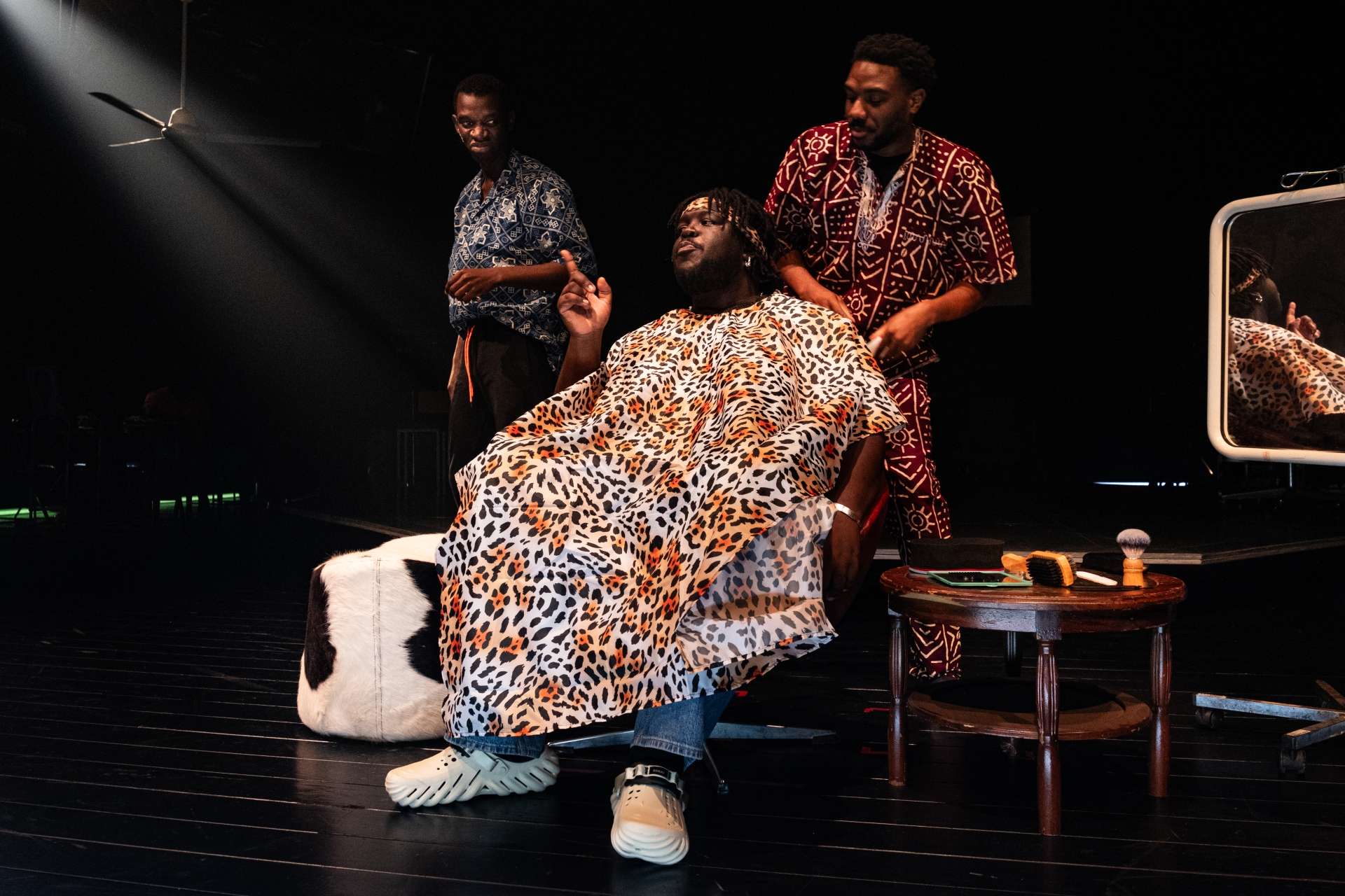 Barber Shop Chronicles © Stef Stessel 3 hommes noirs chez le barbier dont l'un assis