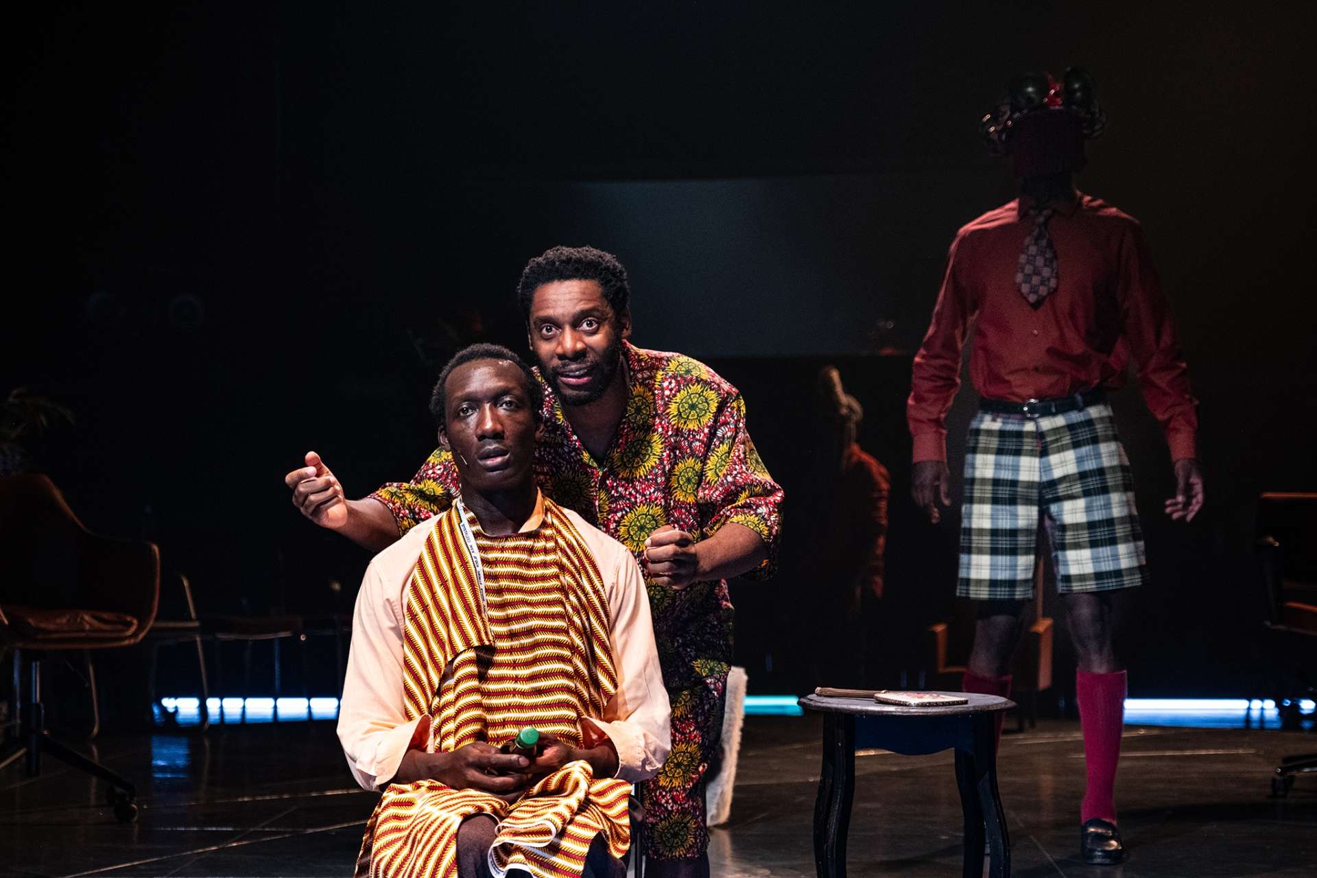 Barber Shop Chronicles © Stef Stessel 3 hommes noirs dont l'un assis chez le barbier