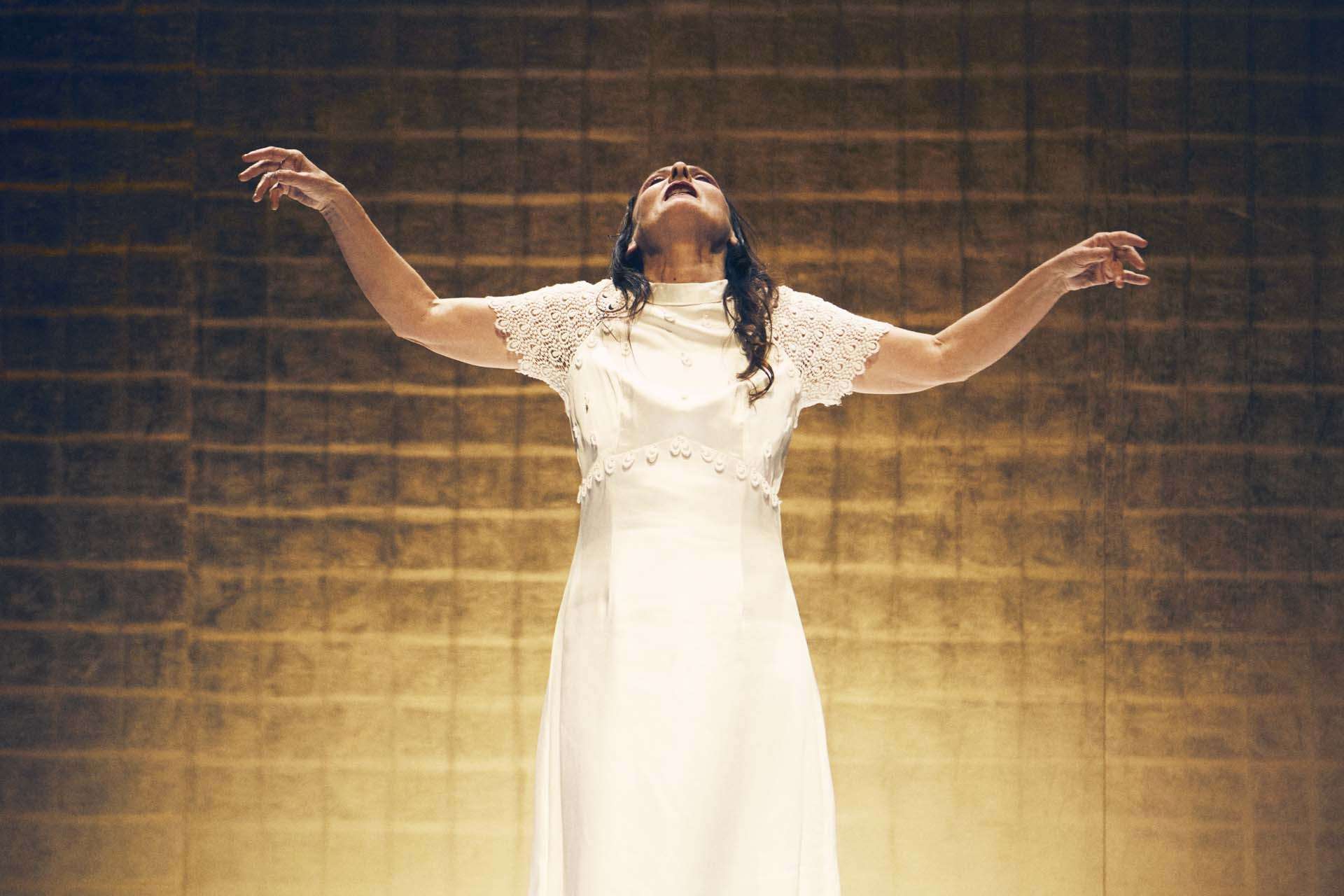 Seppuku Angelica Liddell © Ximena y Sergio femme seule debout vetue blanc fond de scene doré bras en croix tete relevée vers l'arrière